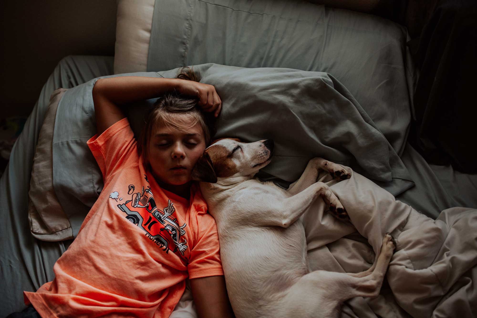 kid and a dog sleeping in bed.