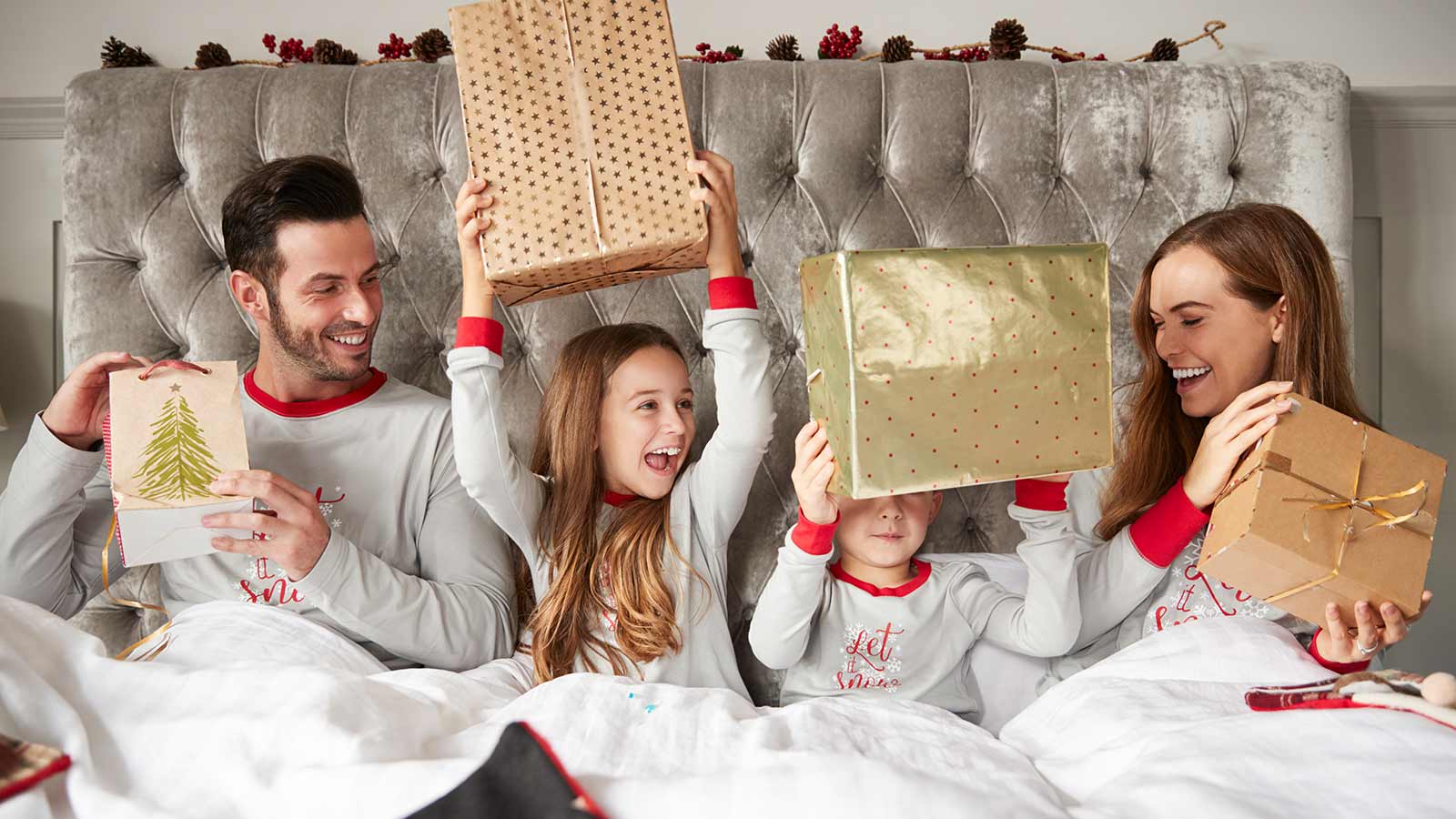Family in bed opening Christmas gifts