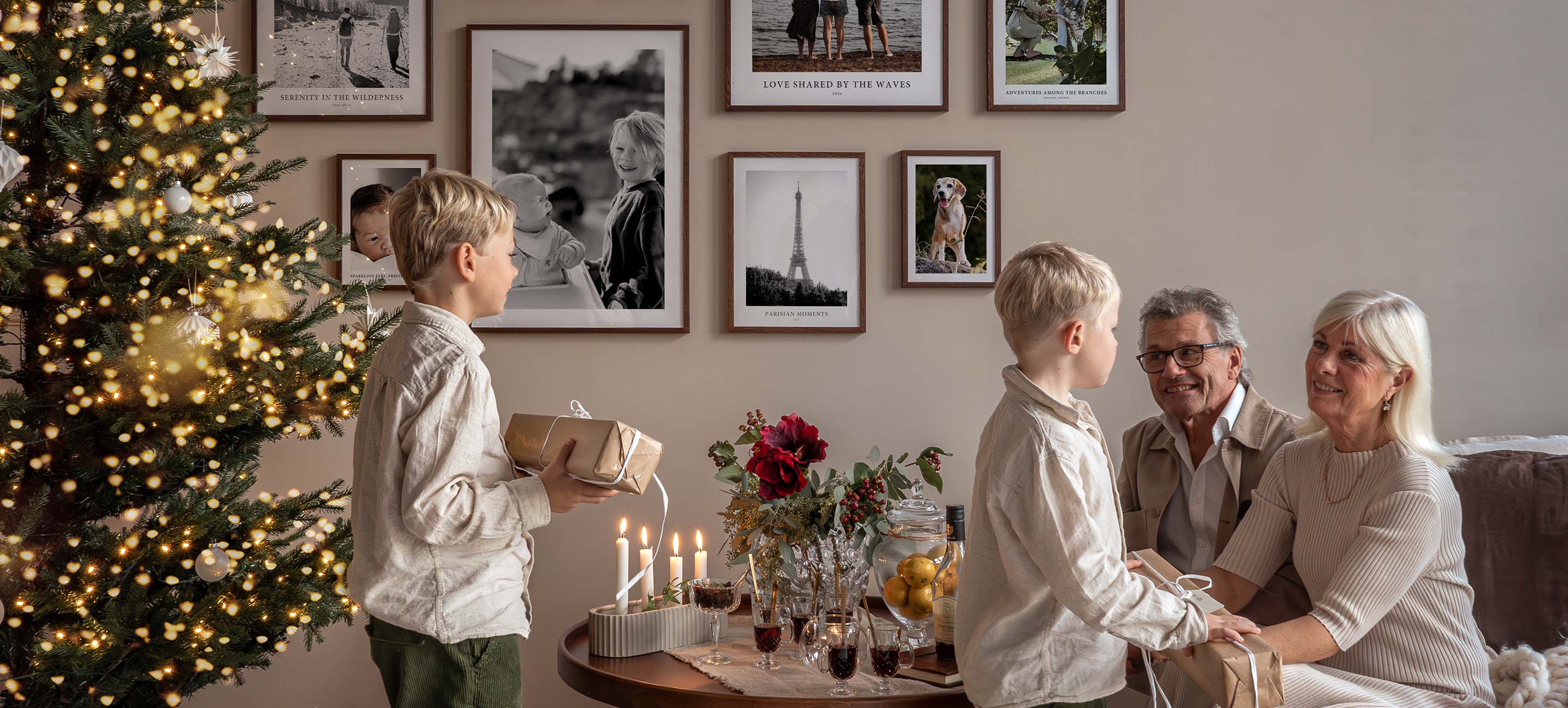 Family giving Christmas gifts with gallery wall of photo posters in background