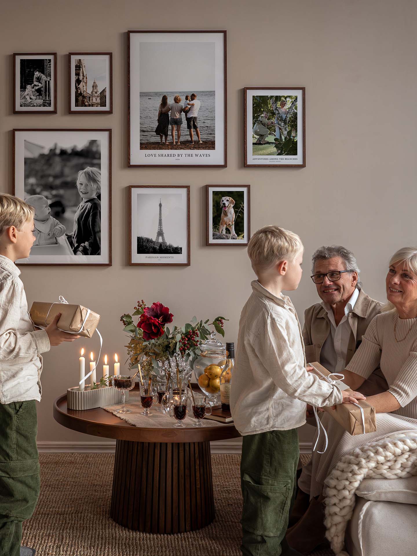 Family giving Christmas gifts with gallery wall of photo posters in background